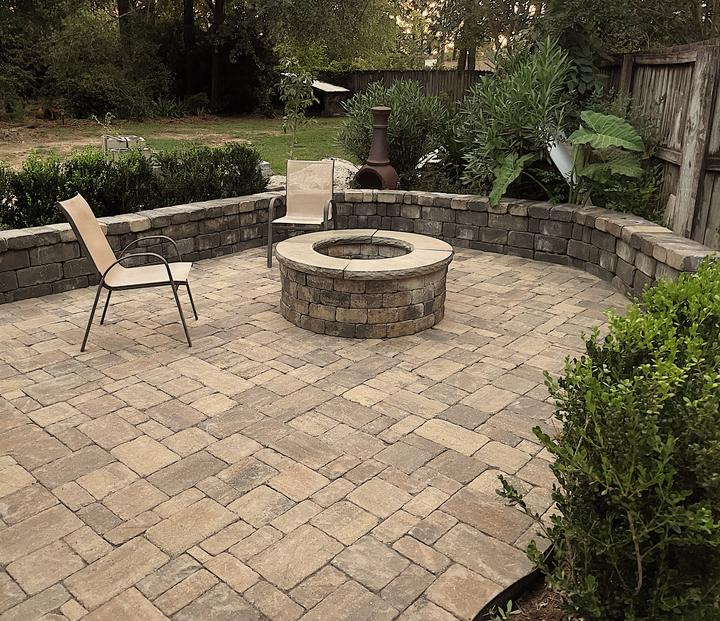 Paver patio with a round stone fire pit and curved seat wall
