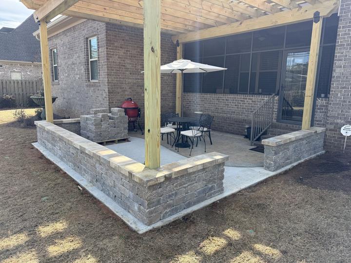 Wood pergola and stone block seat wall around a backyard patio