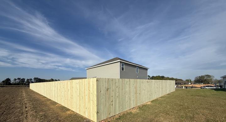 Tall wood privacy fence surrounding the yard of a new two-story home