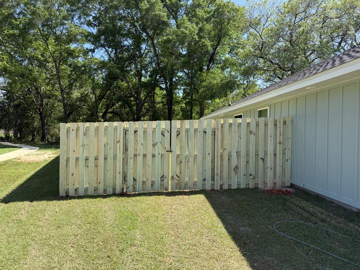 Shadowbox wood fence with a double gate beside a home