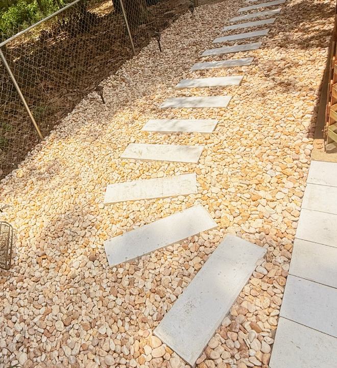 Diagonal stepping stones set in tan gravel along a side yard