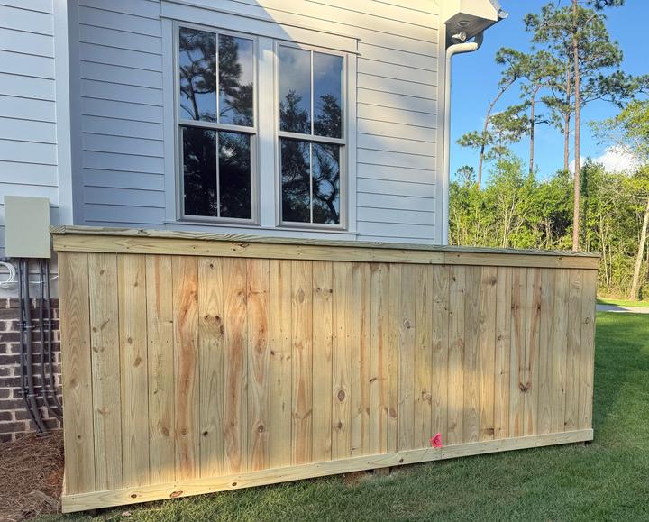 New pressure-treated wood privacy fence beside a home with gray siding