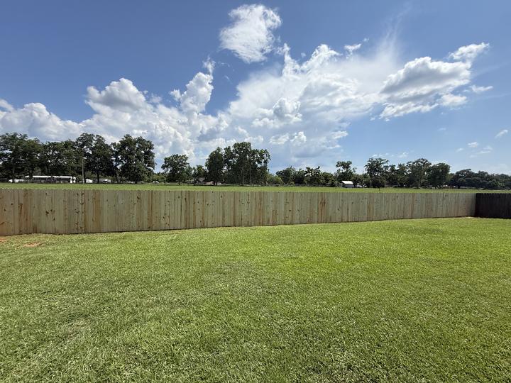 Long wood privacy fence enclosing a wide backyard